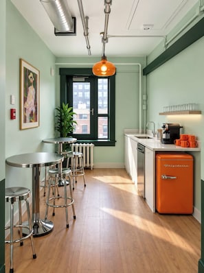 A kitchen with a radiator, a window, a sink, and a compact refrigerator. - The Solitaire Hotel (Vancouver)