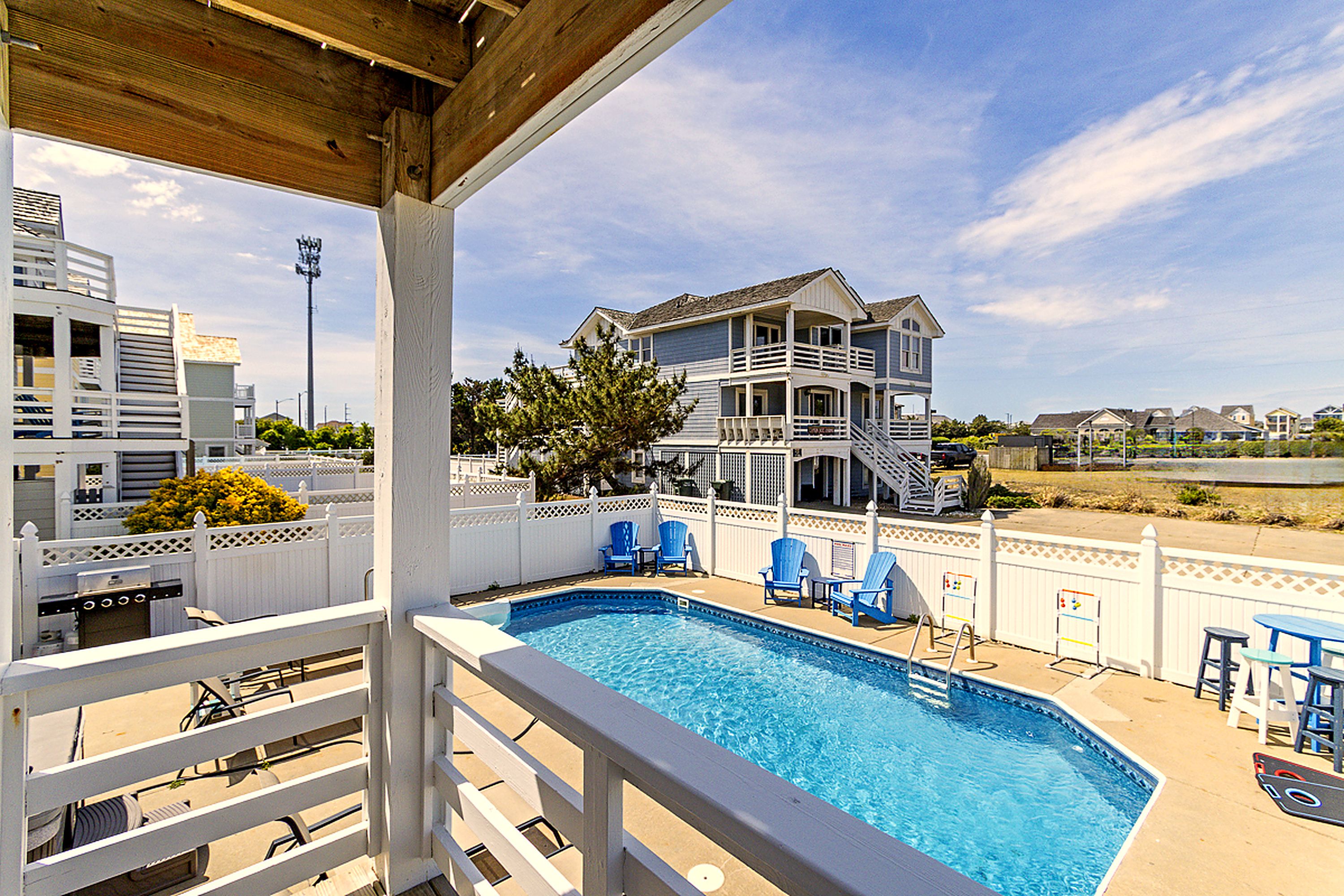 A swimming pool with lounge chairs and a view of a two-story house with a balcony.