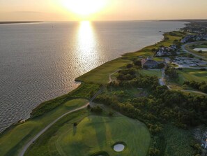 Luftaufnahme eines Golfplatzes mit einem großen Wasserspiegel an einer Seite und einer Wohngegend an der anderen.