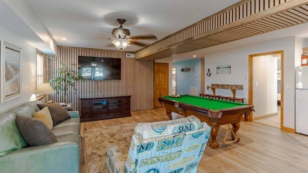 A living room with a pool table, a sofa, a TV, and a ceiling fan. - 🏖️ Luxury 8BR🌊 Ocean Views💦 Free Pool Heat♨️ Elevator🐾2nd Row✨Pet Friendly (Nagshead)