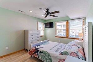 A bedroom with a bed, dresser, ceiling fan, TV, and windows. - 🏖️ Luxury 8BR🌊 Ocean Views💦 Free Pool Heat♨️ Elevator🐾2nd Row✨Pet Friendly (Nagshead)