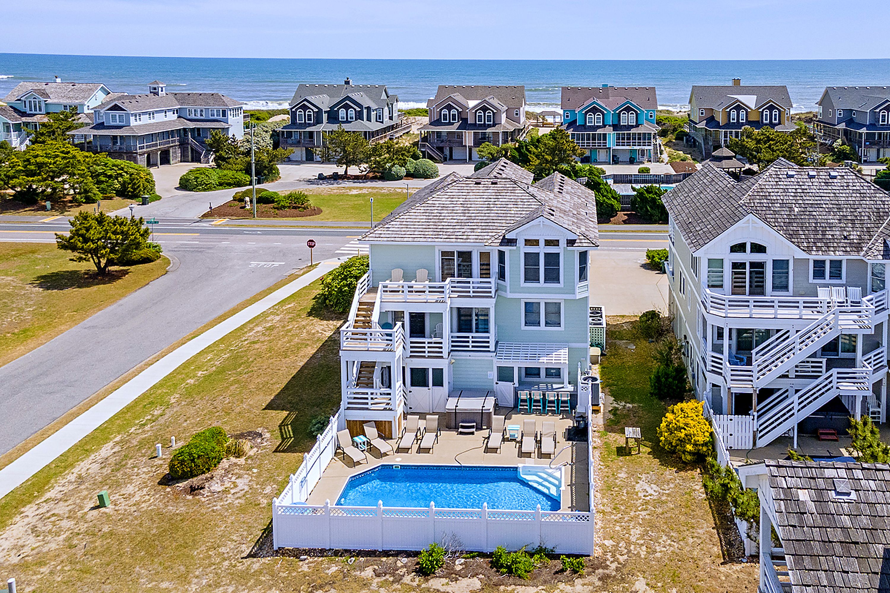 A coastal residential area with multiple houses, a swimming pool, and a road.