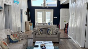 En stue med en loftventilator, en sofa, et sofabord og udsigt ud