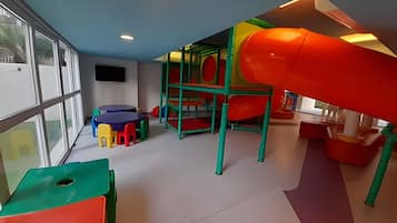 Zona de juegos con tobogán, estructuras para escalar y asientos de colores.