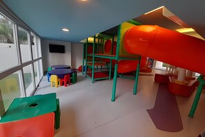 Un'area giochi con scivolo, strutture per arrampicata e sedute colorate.