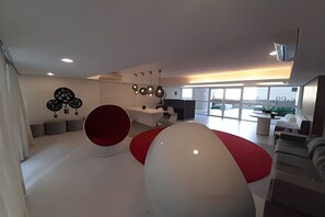 Un intérieur moderne avec un grand espace de détente sphérique aux couleurs blanc et rouge, un canapé blanc et un luminaire fixé au mur.