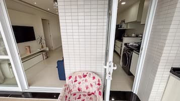 Een moderne keuken met witte tegels, een wasmachine en een televisie aan de muur.