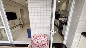 Una cocina moderna con baldosas blancas, una lavadora y un televisor montado en la pared.