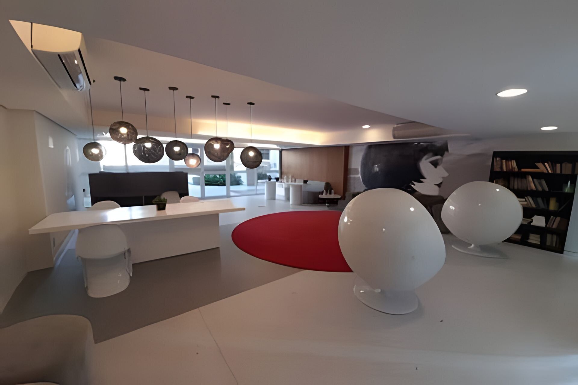 Un interior moderno con una zona de comedor central, una cocina y un área de estar con un tapete rojo.