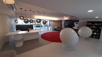 Un interior moderno con una zona de comedor central, una cocina y un área de estar con un tapete rojo.
