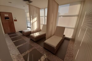 Habitación de hotel con un ventanal grande, una cama, una silla y una mesita.