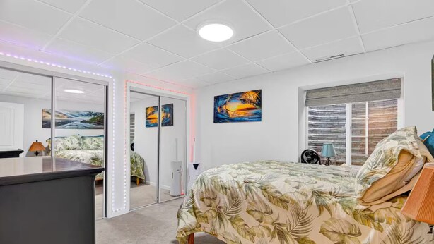 A bedroom with a bed, a desk, a mirror, and artwork on the walls. - The little Beach House in the Forest (Colorado Springs)