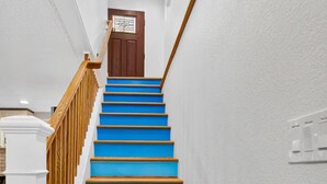 A staircase with blue steps and wooden handrails leading to a door. - The little Beach House in the Forest (Colorado Springs)