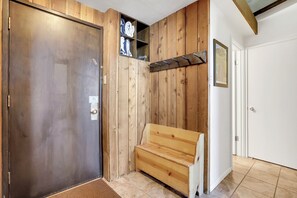 Ein Flur mit Holzwand, einer Metalldür, einer Bank und einem Regal mit Handtüchern.