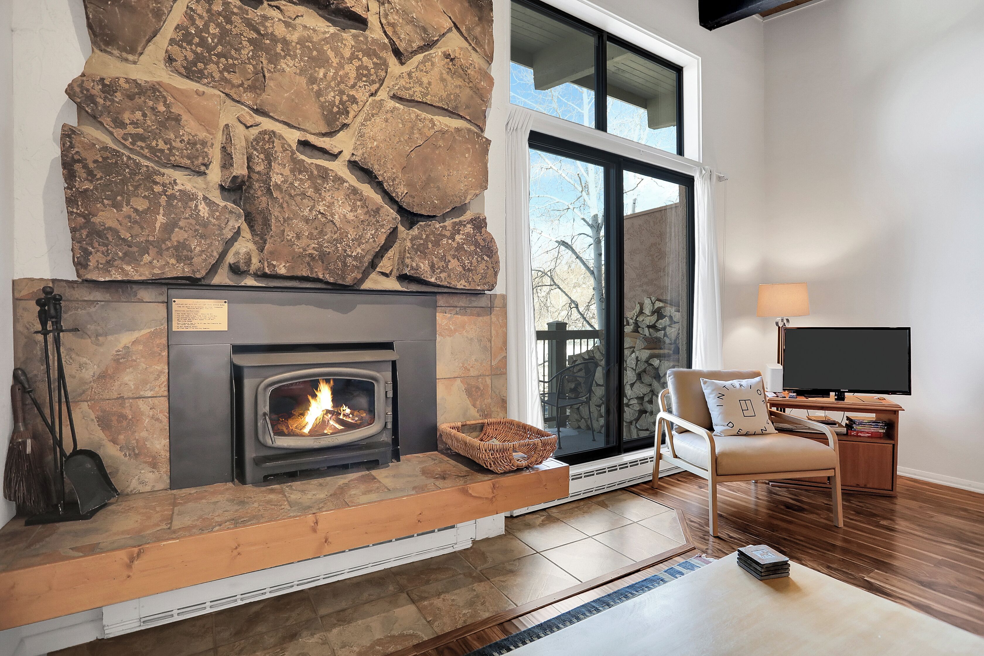 A living room with a stone fireplace, a television, and a comfortable seating area.