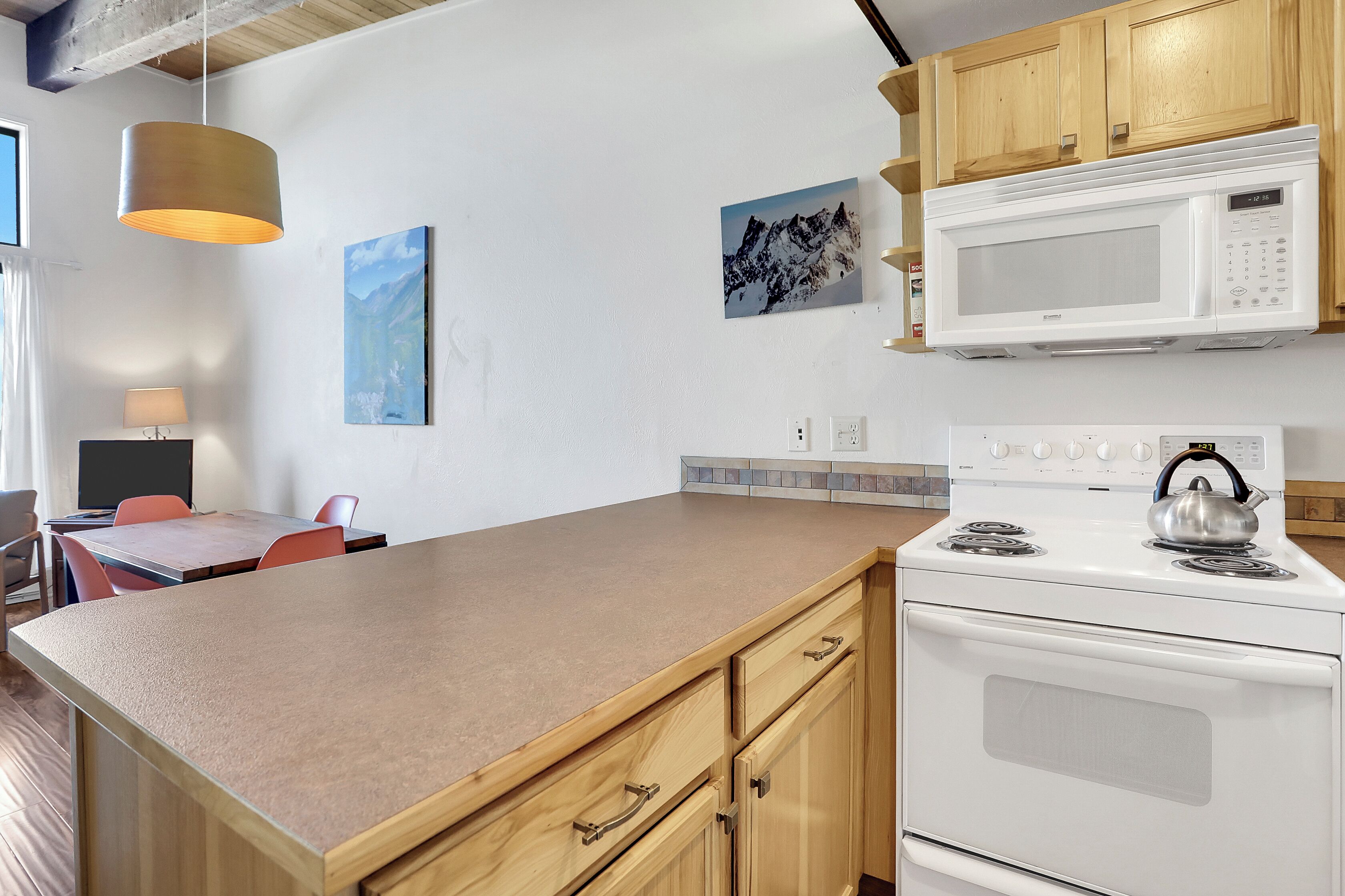 Una cocina con armarios de madera, estufa blanca, microondas y una isla grande con hervidor.