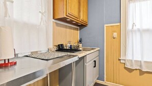Una kitchenette compacta con encimera, lavamanos y armarios de madera.