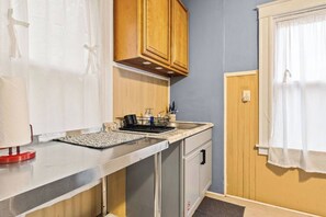 Eine kleine Küchenzeile mit Arbeitsplatte, Spüle und Holzschränken.