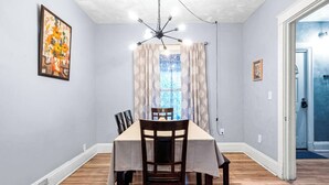 Comedor con mesa, sillas, candelabro y ventana con cortinas.