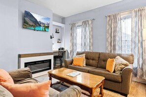 Una sala de estar con un sofá, una mesa de centro, una chimenea y un cuadro en la pared.