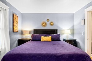 Un dormitorio con una cama grande, dos mesitas de noche, un cabecero y decoración en la pared.