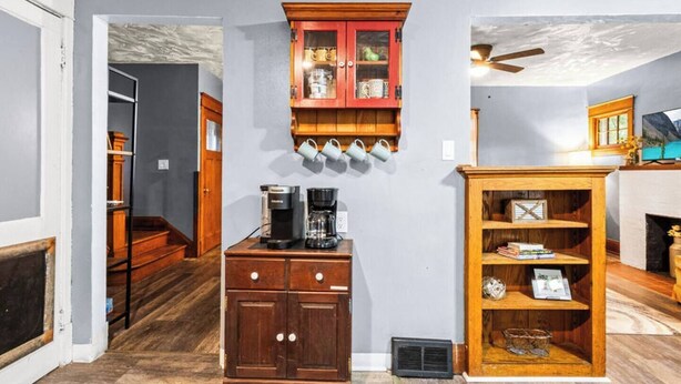 Una habitación con un armario de madera, una cafetera y una estantería.