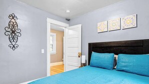 Un dormitorio con cama, puerta y un adorno en la pared.