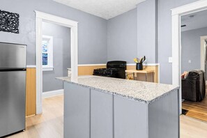 Cocina moderna con paredes grises, encimera de granito y refrigerador de acero inoxidable.
