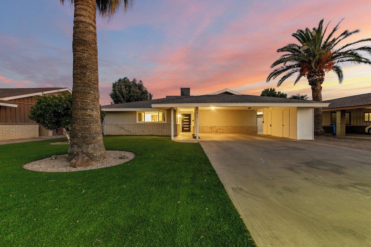 A residential house with a garage, a well-maintained lawn, and a palm tree.