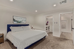 A bedroom with a bed, a nightstand, a wall-mounted painting, and a closet with open doors. - Desert Paradise: Pool, Hot Tub, Sauna & Minigolf (Chandler)