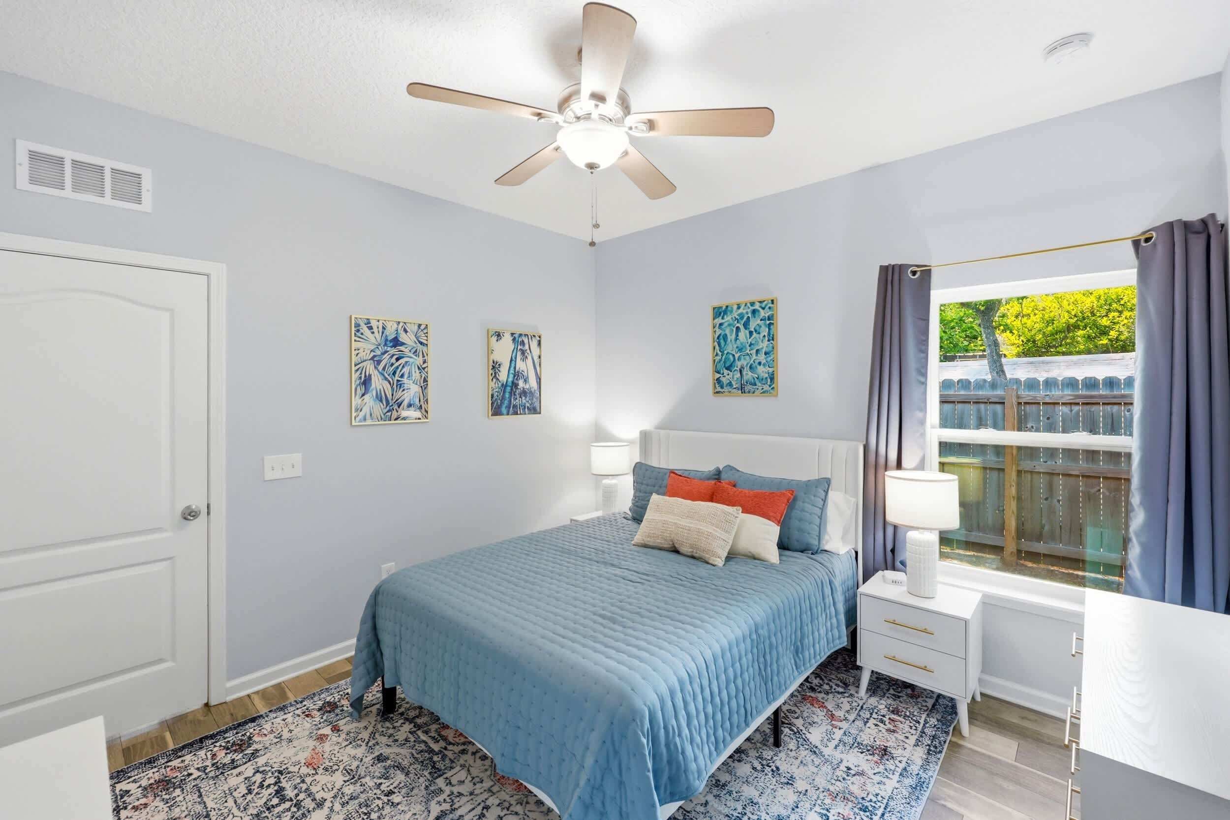 A bedroom with a bed, bedside tables, a ceiling fan, and a window with curtains.