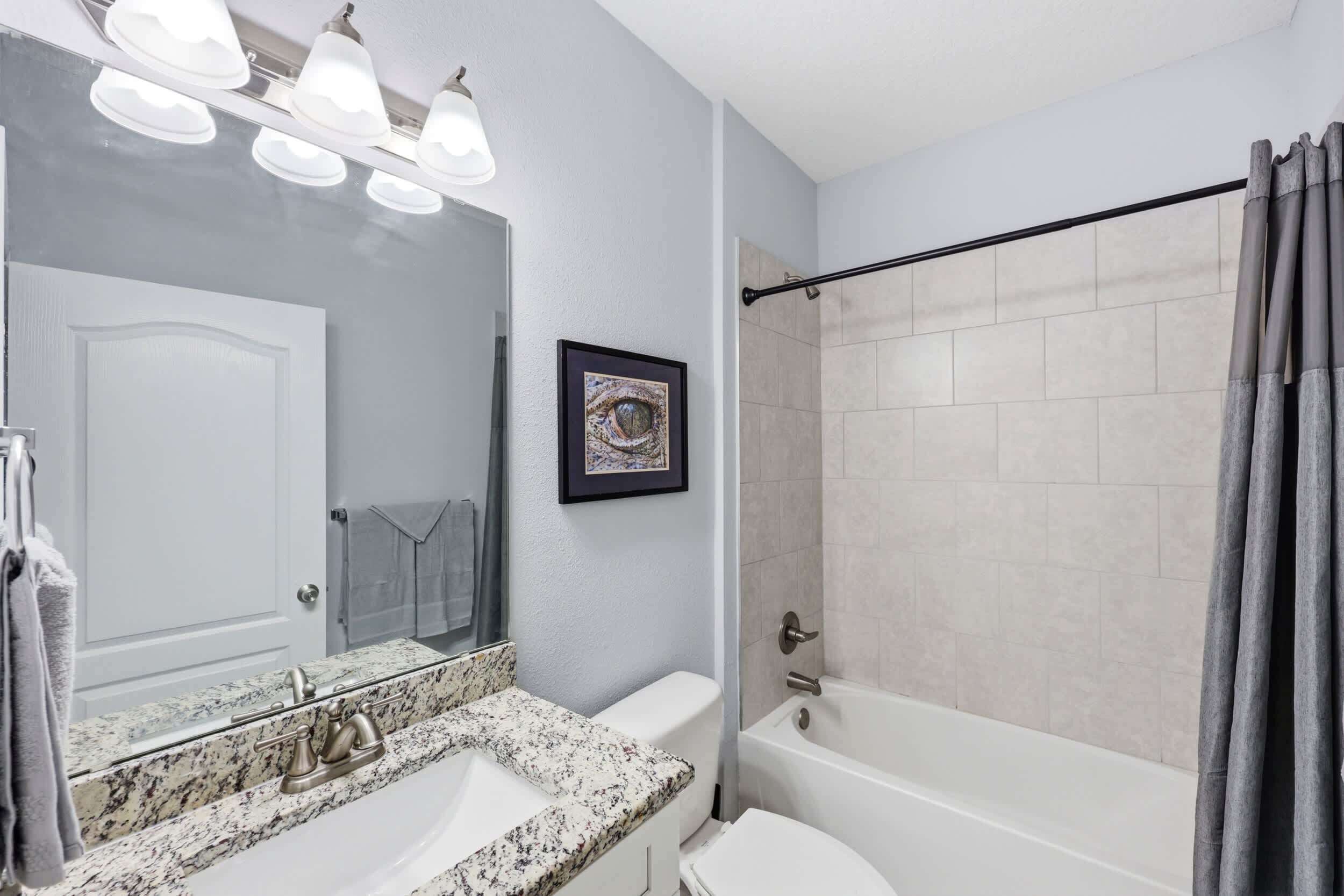 A bathroom with a sink, mirror, toilet, and bathtub.