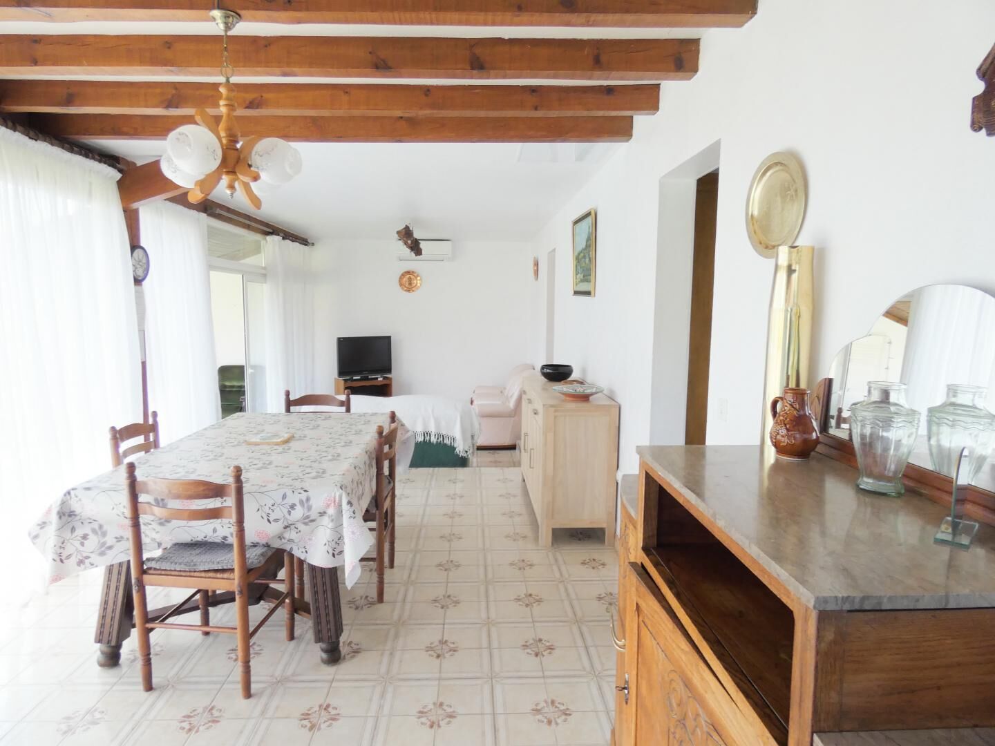 A dining area with a table, chairs, a ceiling fan, and a kitchen area with cabinets and a countertop.