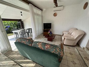 Ein Wohnzimmer mit einer Couch, einem Fernseher und einem Essbereich mit Stühlen und einem Tisch.
