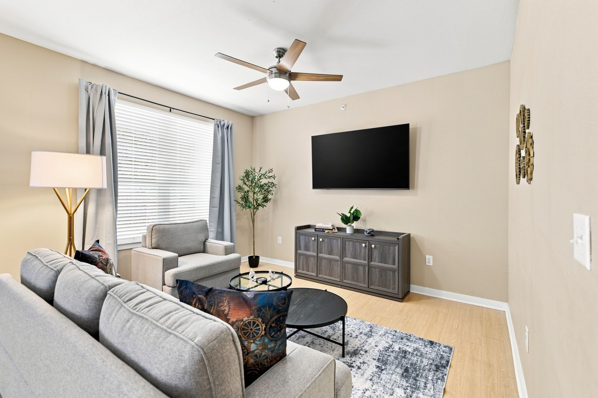 Un salon comprenant un canapé, une table basse, un téléviseur, un ventilateur de plafond et un meuble.