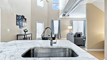 A modern kitchen with a marble countertop and a stainless steel sink.