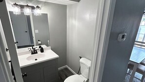 Un bagno con il water, un lavandino e uno specchio.