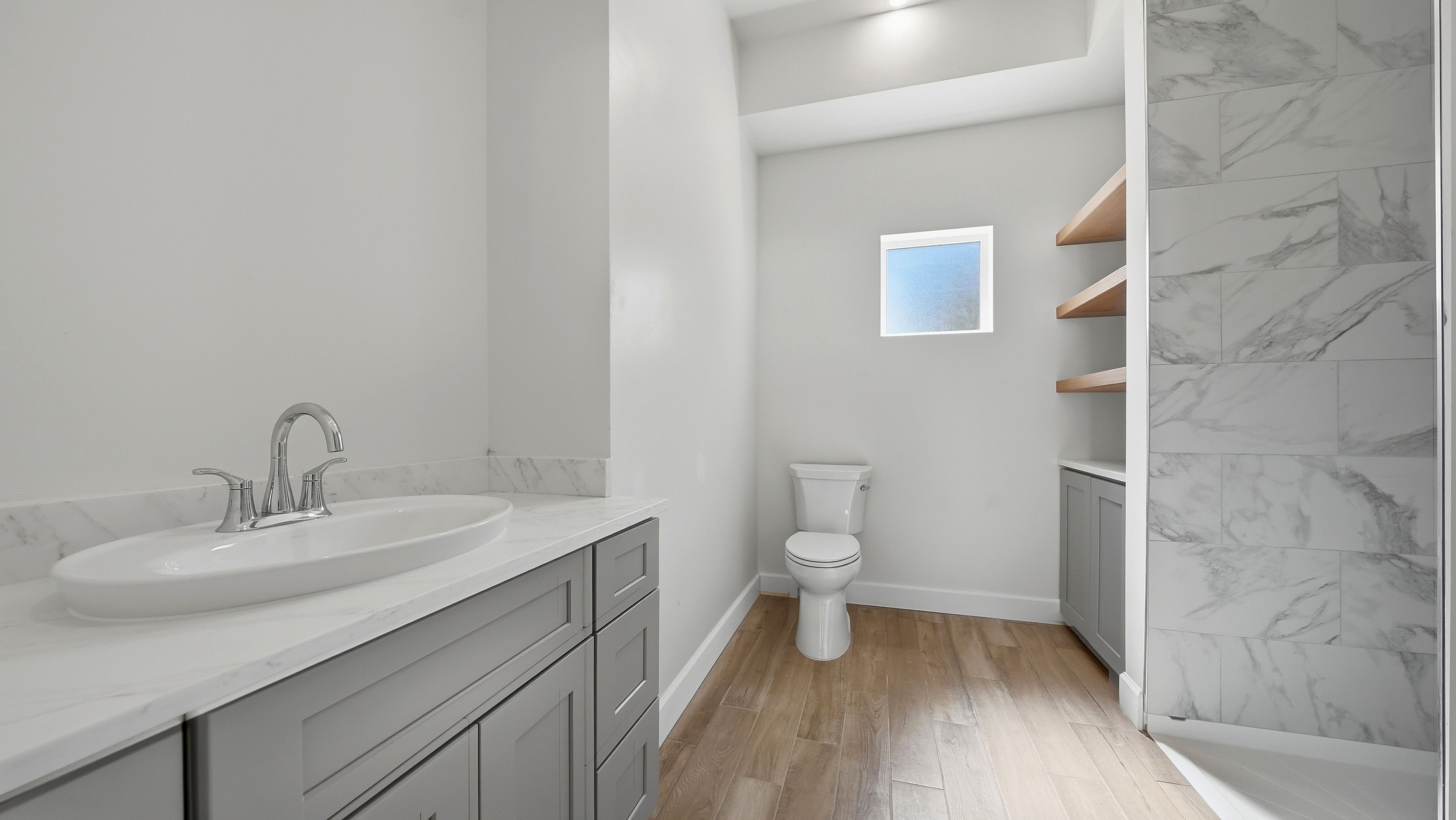 Une salle de bain avec un lavabo, des toilettes et des étagères en bois.