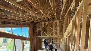 Een bouwplaats met zichtbare houten constructie, gereedschap en werklieden.