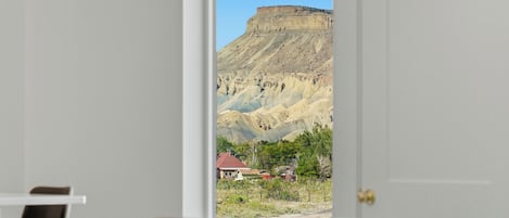 Un dormitorio con una cama y una puerta que da a vistas de un paisaje montañoso.