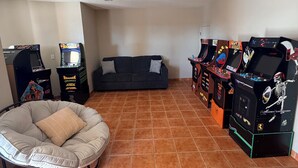 Una habitación con sofá, sillón de saco y varias máquinas de videojuegos.