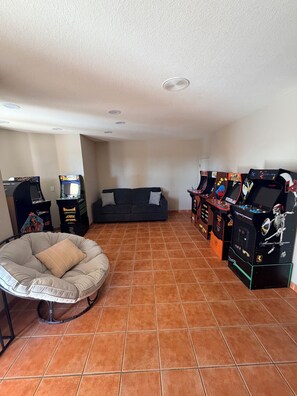 Una habitación con sofá, sillón de saco y varias máquinas de videojuegos.