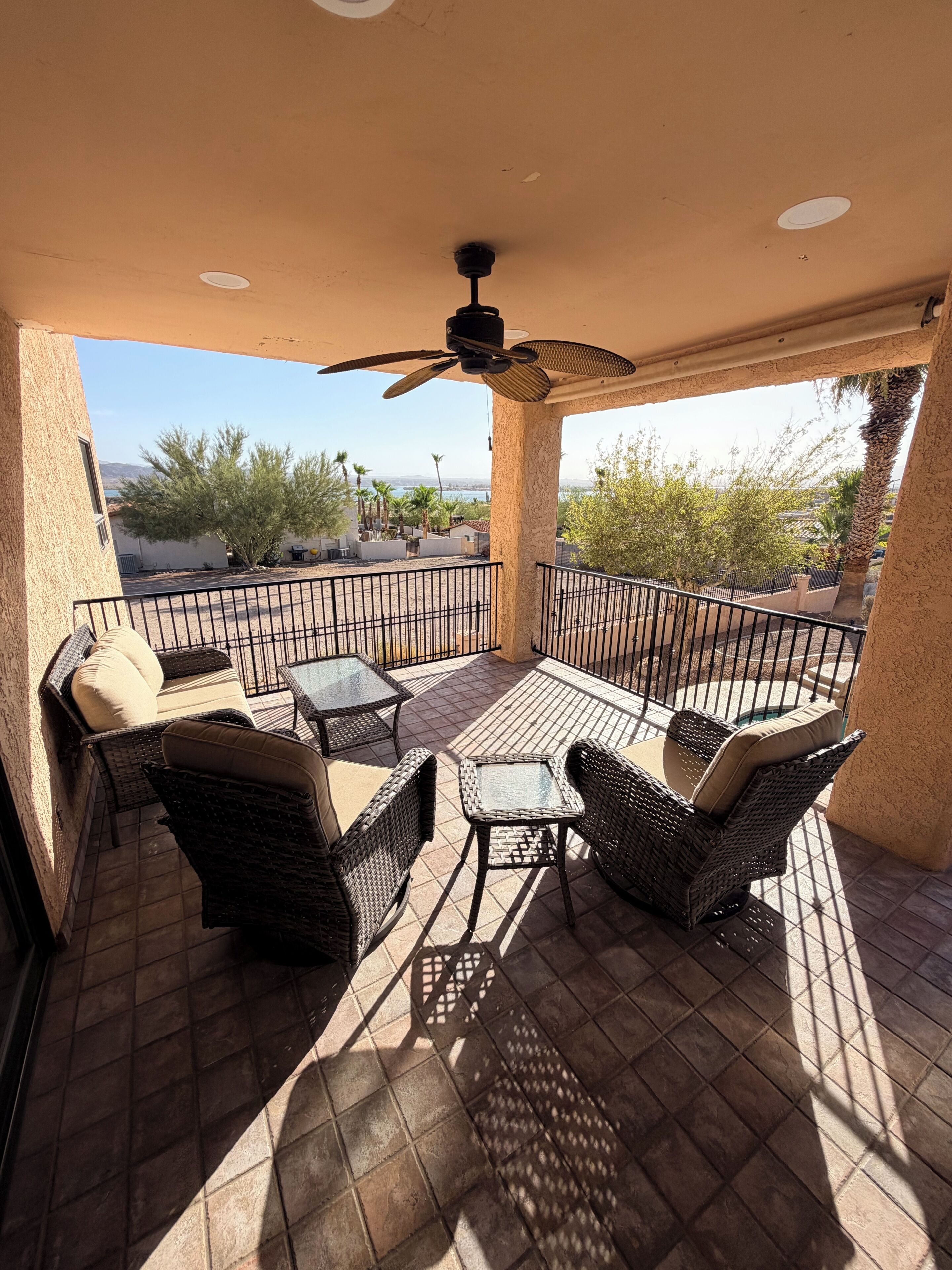 A balcony with wicker furniture, a ceiling fan, and a view of a desert landscape.
