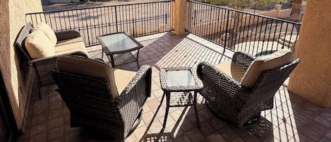 A balcony with wicker furniture, a ceiling fan, and a view of a desert landscape.