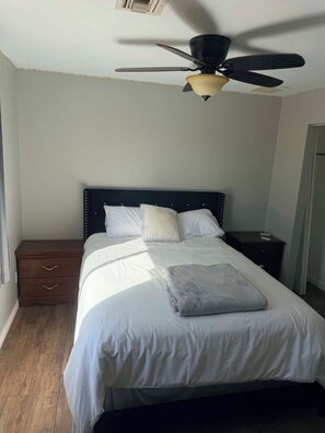 A bedroom with a bed, a nightstand, a drawer unit, and a ceiling fan. - Large home panoramic lake views, boat parking, pool, game room, ice machine! (Lake Havasu City)