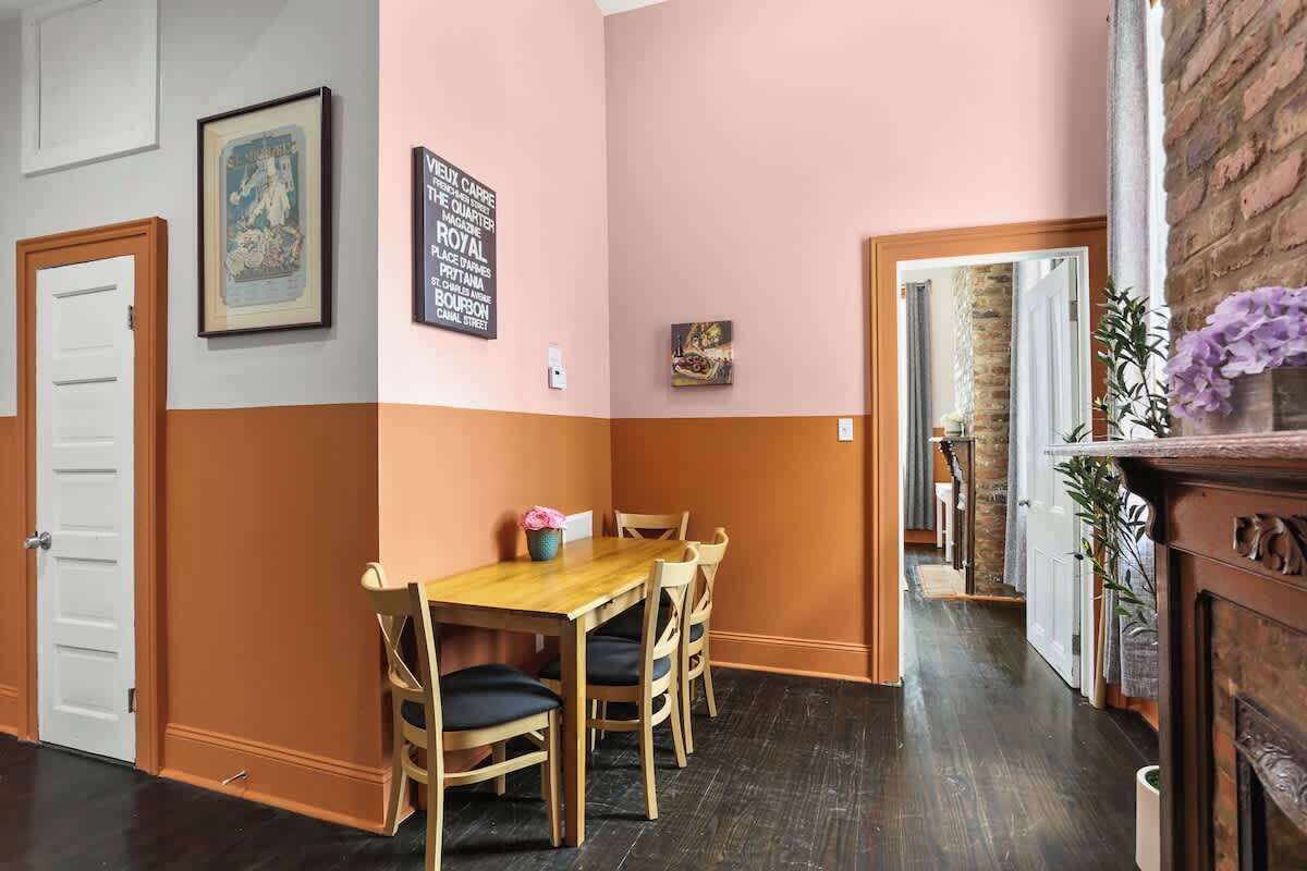 Ein Essbereich mit einem Holztisch und -stühlen, einem gerahmten Bild an der Wand und einem Kamin aus Backsteinen.