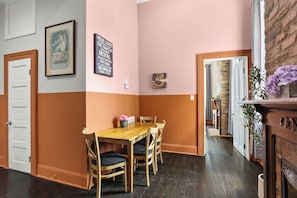 A dining area with a wooden table and chairs, a framed picture on the wall, and a brick fireplace. - Explore NOLA: Studio 6 Blocks from French Quarter (New Orleans)