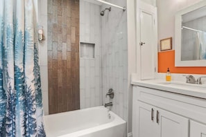 A bathroom with a bathtub, shower, and a vanity with a mirror. - Explore NOLA: Studio 6 Blocks from French Quarter (New Orleans)