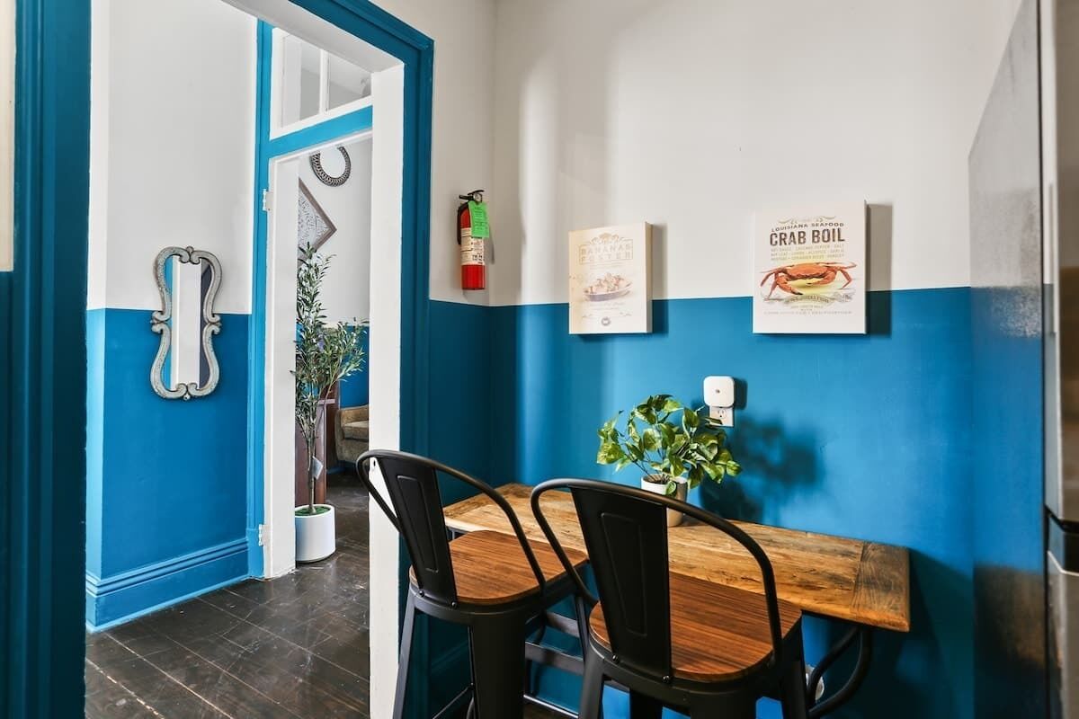 Ein Essbereich mit Holztisch, schwarzen Stühlen, einem Blumentopf und Wandbildern.