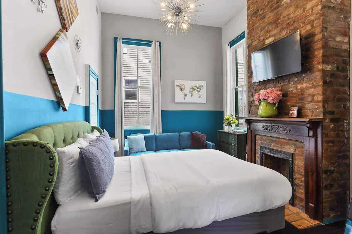 Ein Schlafzimmer mit einem Bett, einer Kommode, einem an einer Ziegelwand montierten Fernseher und einem Kamin.